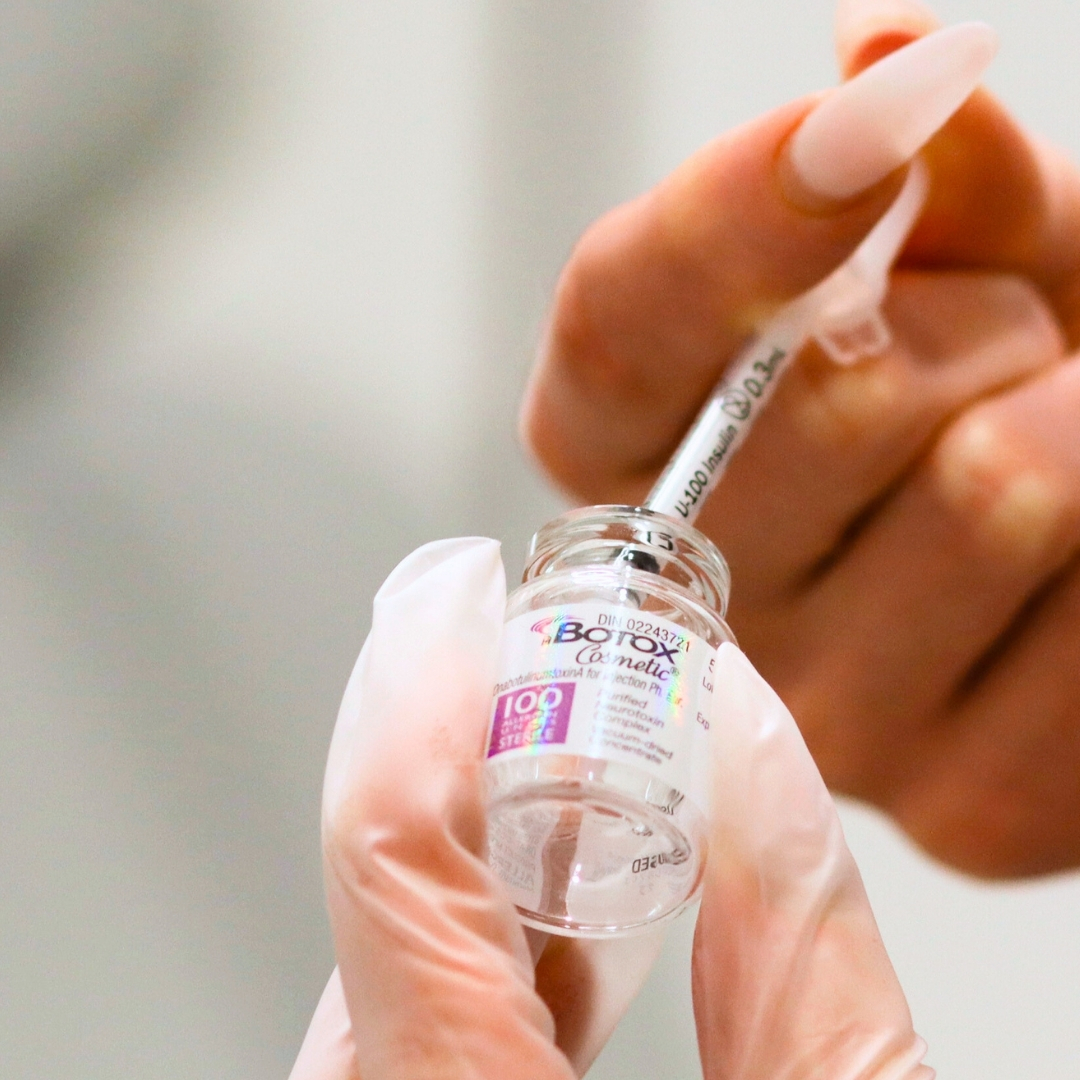 Injector's hands filling up syringe of Botox